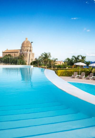 Spiaggia affollata con ombrelloni colorati e bagnanti in acqua vista dall'alto.